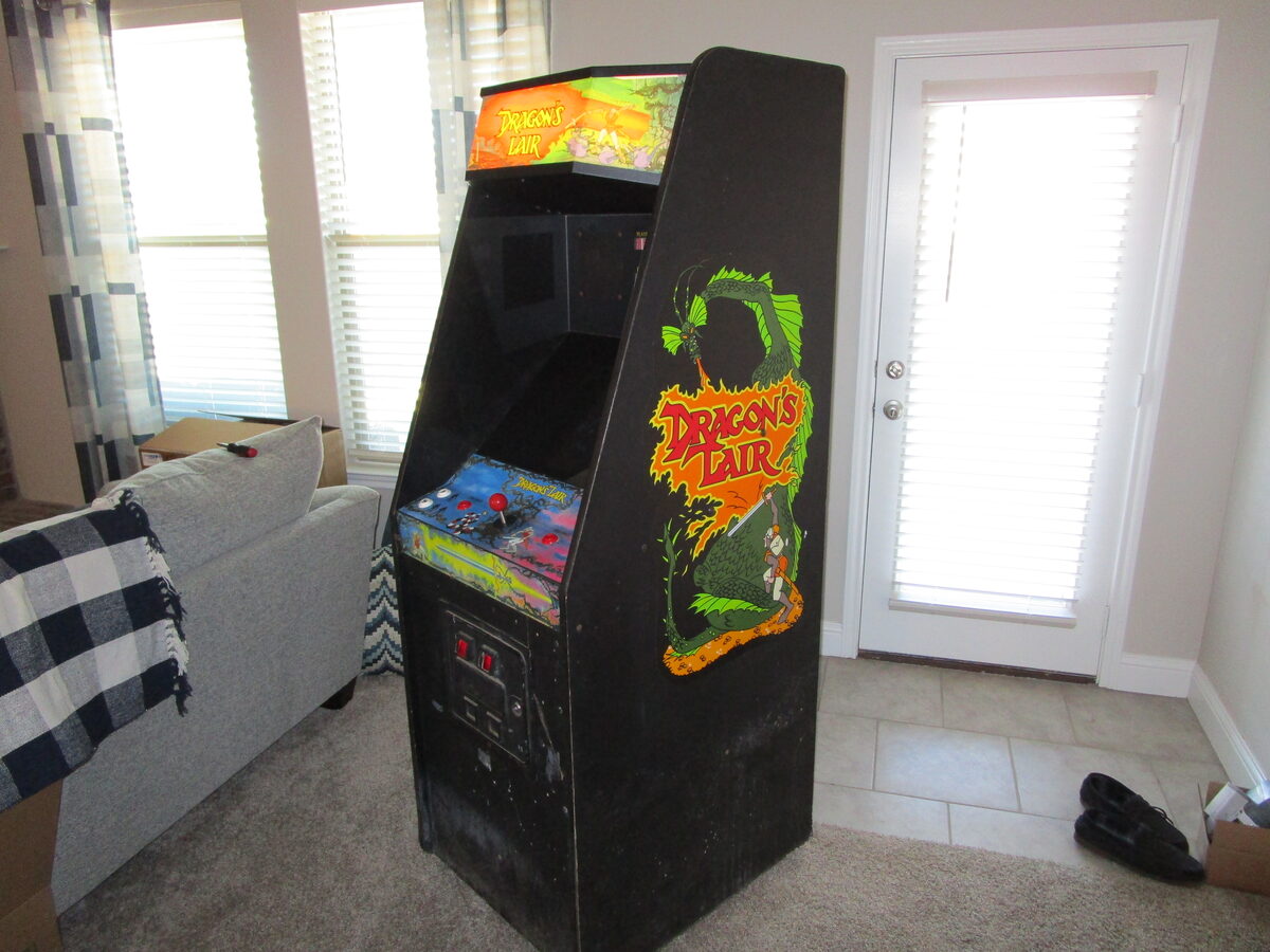 A restored Dragon's Lair arcade cabinet with its iconic green dragon side art, lit marquee, and control panel