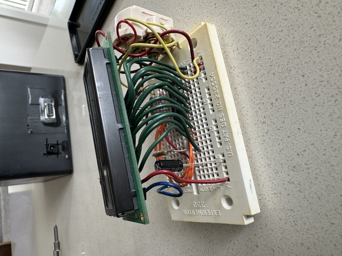 The dashboard LCD module: a character LCD soldered to a small board, wired across a breadboard, base unit behind it